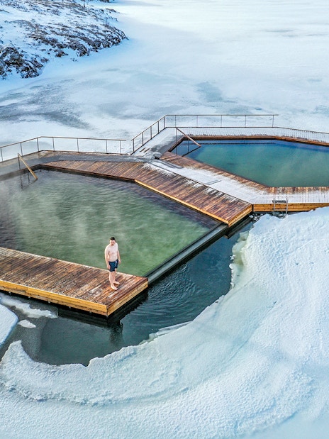 Guests enjoying geothermal pools at Vök Baths, Iceland, surrounded by snow.