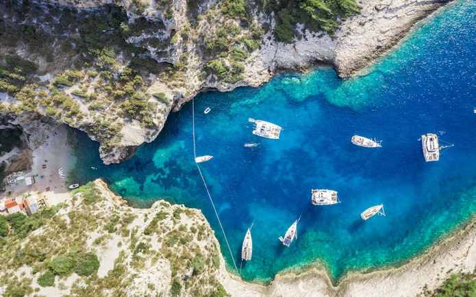 Aerial view of boats in Stiniva Cove, Vis Island, Croatia, surrounded by cliffs and clear Adriatic Sea.