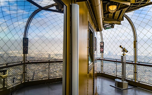 Eiffel Tower summit view with telescope overlooking Paris.