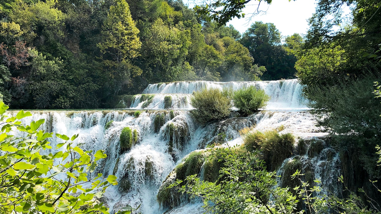 Waterfall at Bilusica Buk in Krka National Park surrounded by lush greenery.