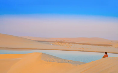 Child sitting on sand dune by Khor Al Adaid, Inland Sea, Doha.