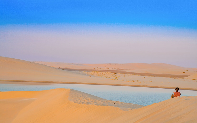 Child sitting on sand dune by Khor Al Adaid, Inland Sea, Doha.