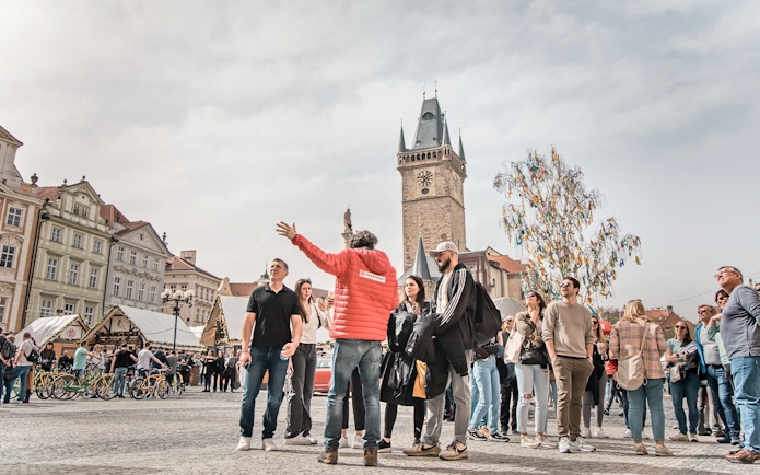 Tour guide leading a group in Prague's Old Town Square near the Astronomical Clock Tower.