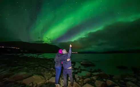Couple watching northern lights over Lake Torneträsk, Abisko.