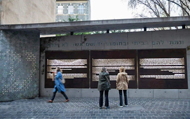 Visitors reading inscriptions at the Ghetto Wall Memorial in Budapest's Jewish Quarter.