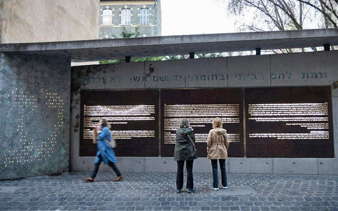 Visitors reading inscriptions at the Ghetto Wall Memorial in Budapest's Jewish Quarter.