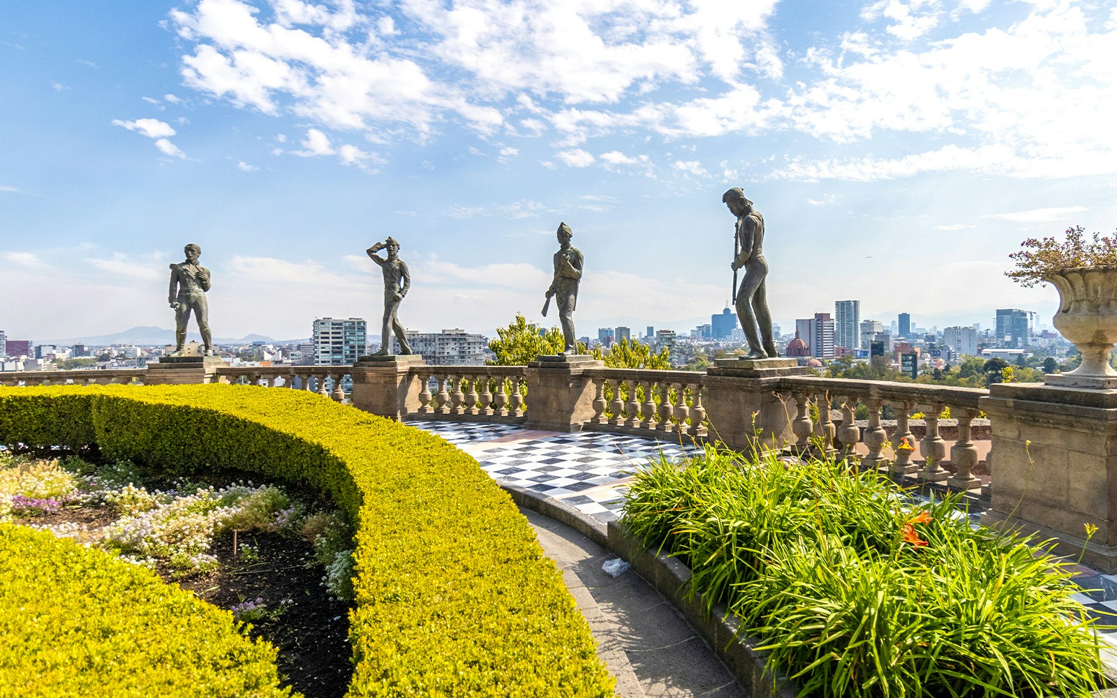Chapultepec Castle with historic statues in Mexico City, surrounded by lush gardens.