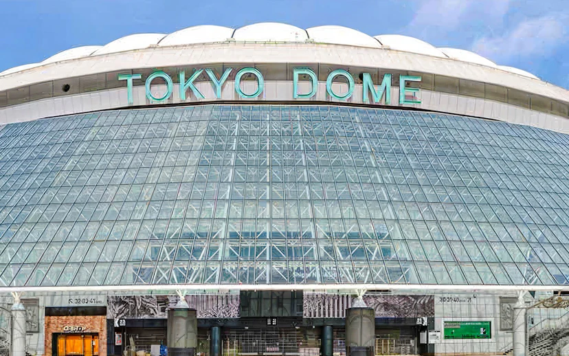 Exterior view of Tokyo Dome with glass facade and entrance.