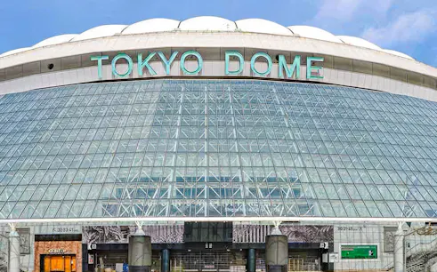 Exterior view of Tokyo Dome with glass facade and entrance.