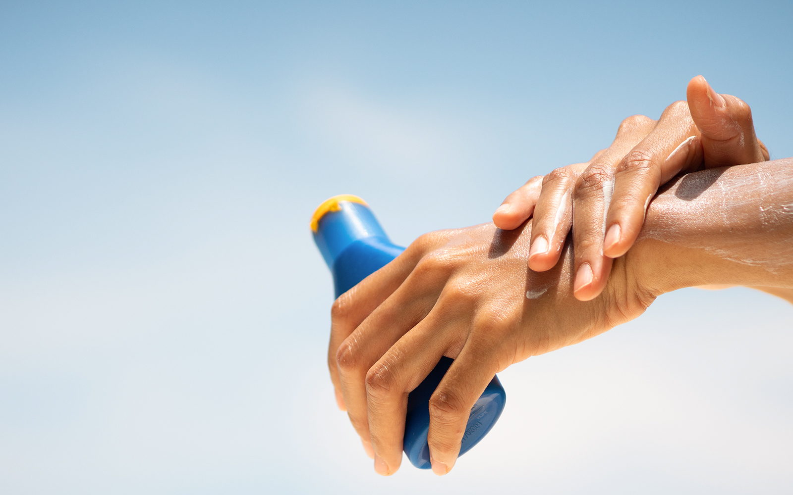 Person applying sunscreen during summer at Dream World