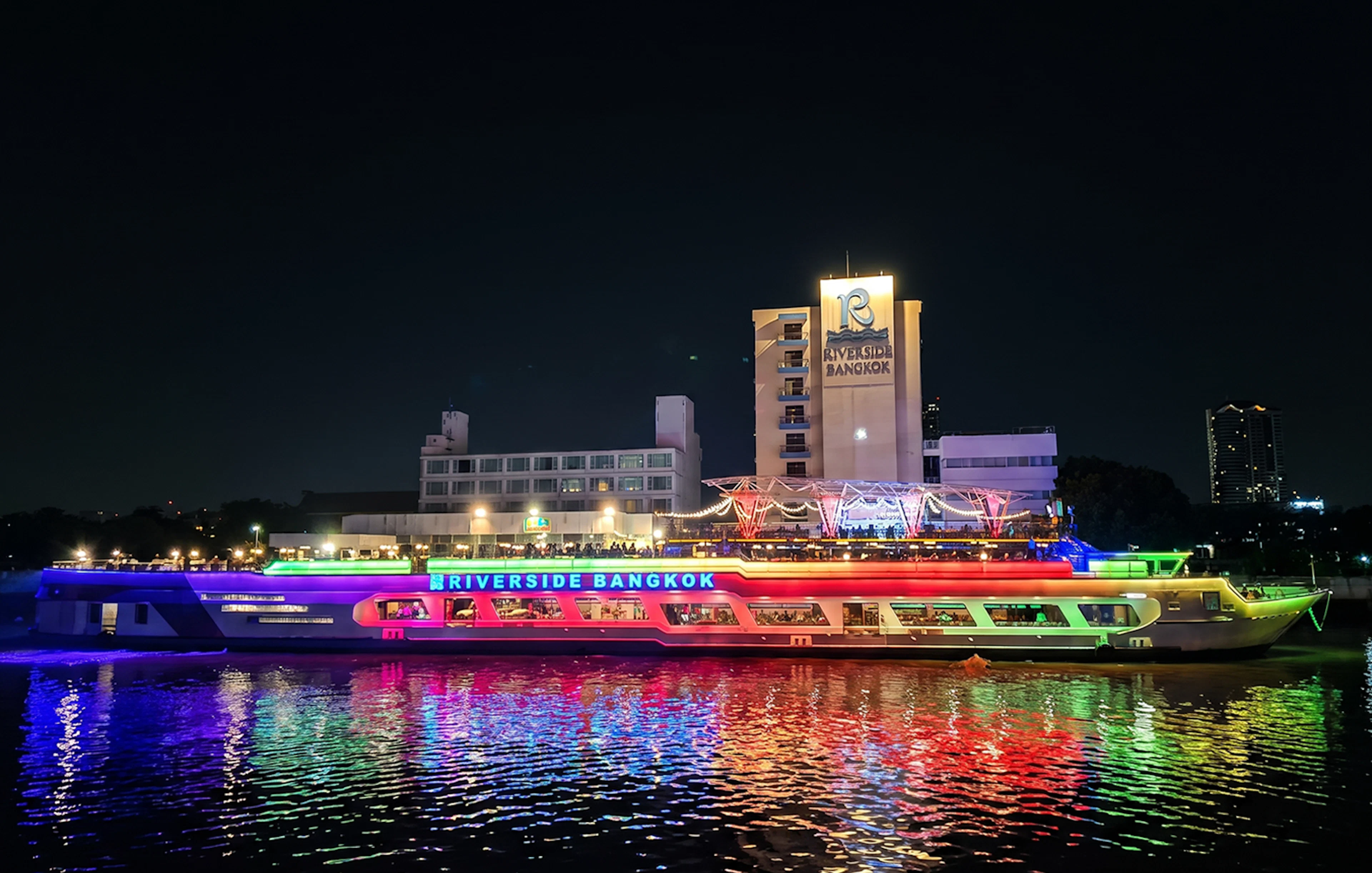 Riverside Carnival Cruise ship illuminated at night in Bangkok.