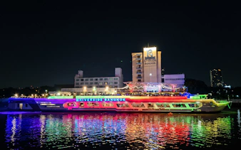 Riverside Carnival Cruise ship illuminated at night in Bangkok.