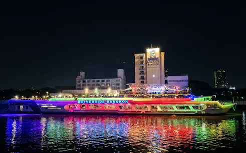 Riverside Carnival Cruise ship illuminated at night in Bangkok.