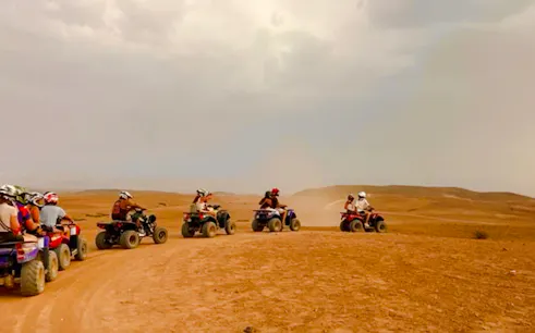 Group riding quad bikes in Marrakech Palmeraie desert.