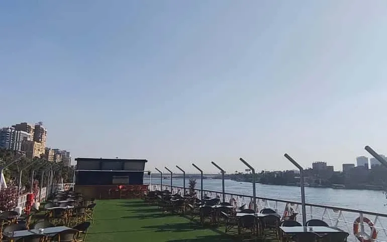 Rooftop view of the Nile River from a Cairo dinner cruise ship with seating area.