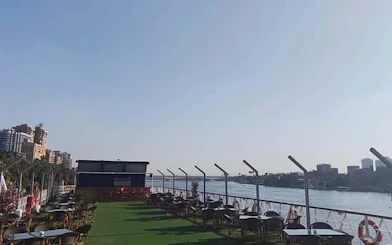 Rooftop view of the Nile River from a Cairo dinner cruise ship with seating area.