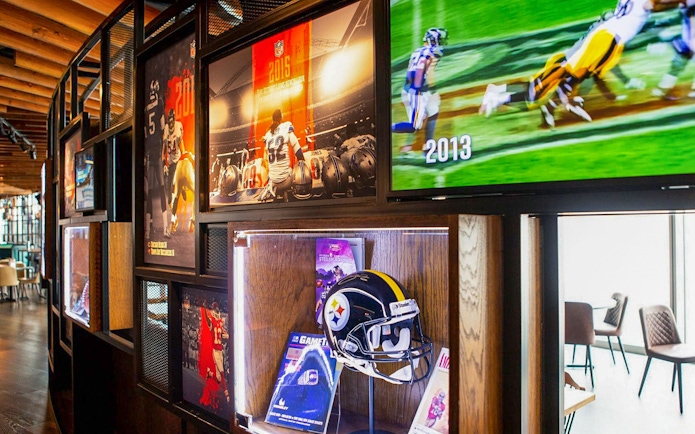 NFL memorabilia display at Wembley Stadium gallery featuring helmets and game footage.