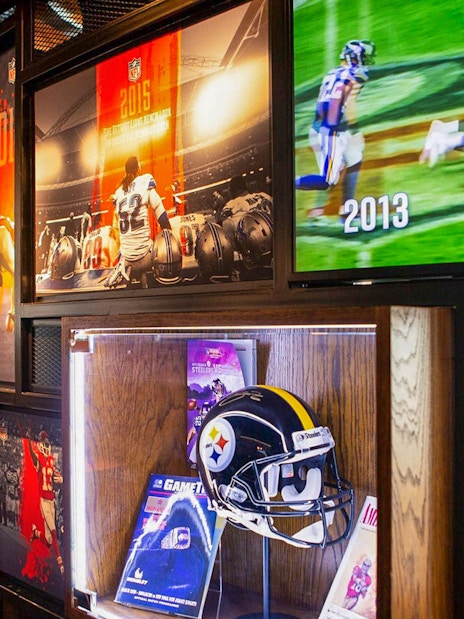 NFL memorabilia display at Wembley Stadium gallery featuring helmets and game footage.