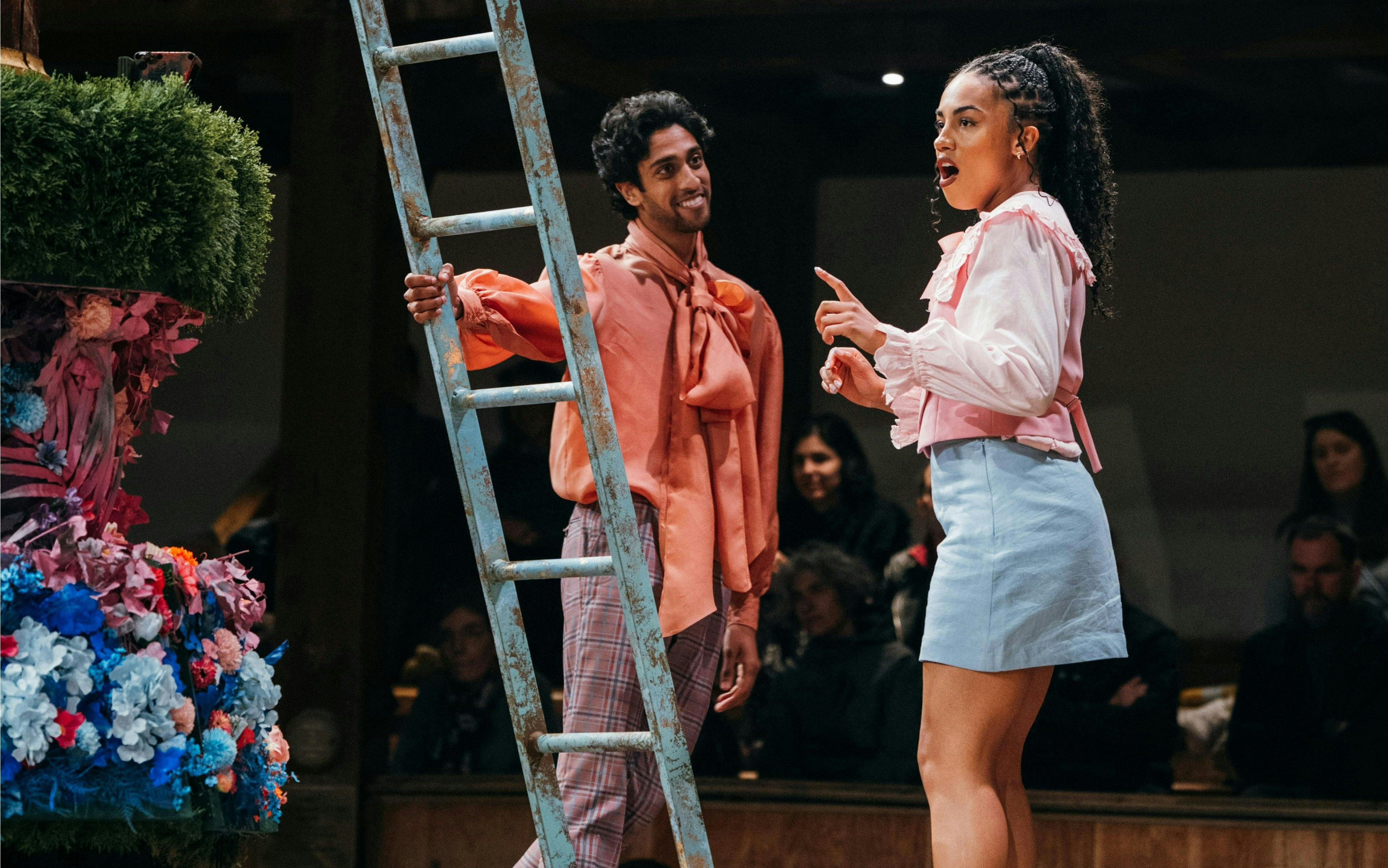 Stage actors performing A Midsummer Night’s Dream, Westend, with colorful floral set.