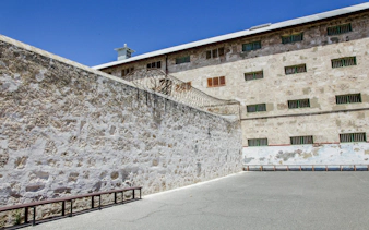 Fremantle Prison courtyard with high stone walls and barbed wire.