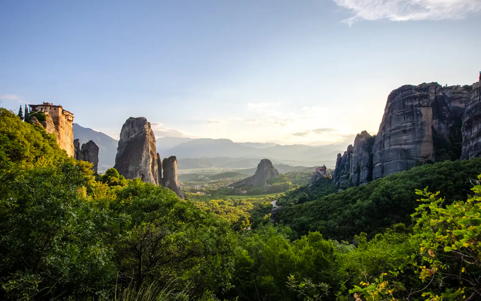 Panoramic view of Meteora monasteries on rocky cliffs in Greece.