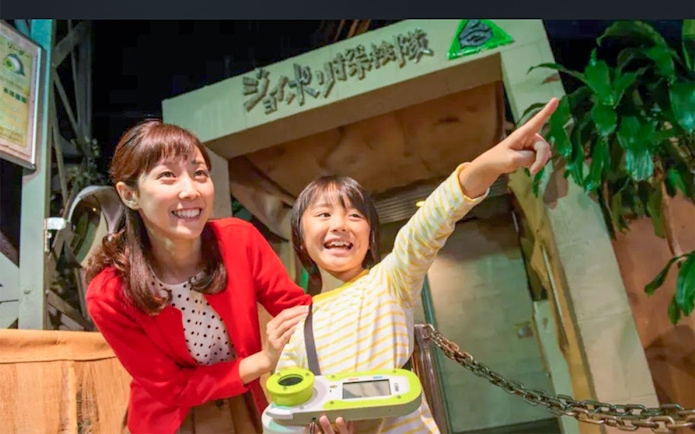 Child and adult excitedly pointing at Tokyo Joypolis Theme Park entrance, Japan.