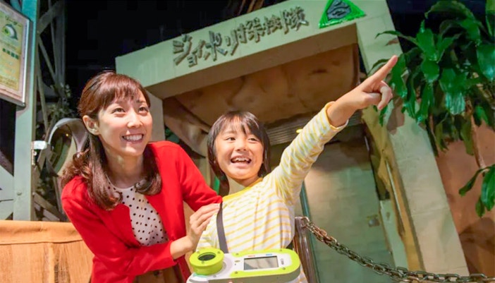 Child and adult excitedly pointing at Tokyo Joypolis Theme Park entrance, Japan.