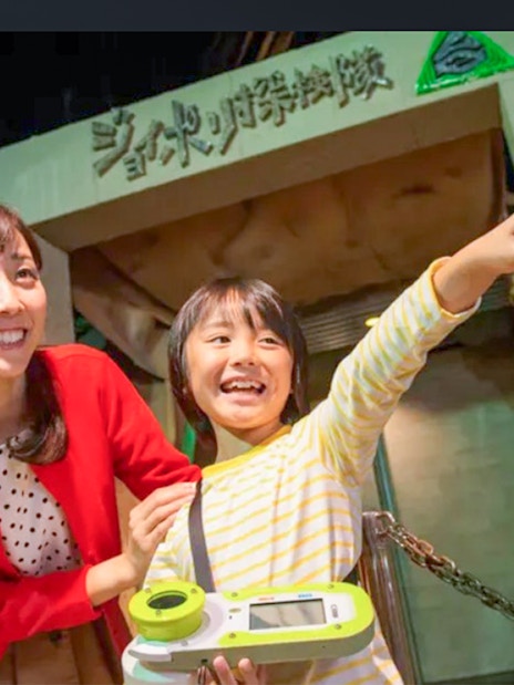 Child and adult excitedly pointing at Tokyo Joypolis Theme Park entrance, Japan.