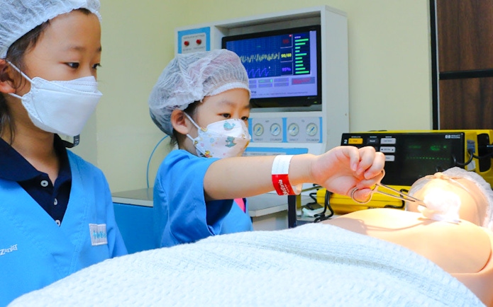 Children practicing surgery at KidZania with medical equipment.