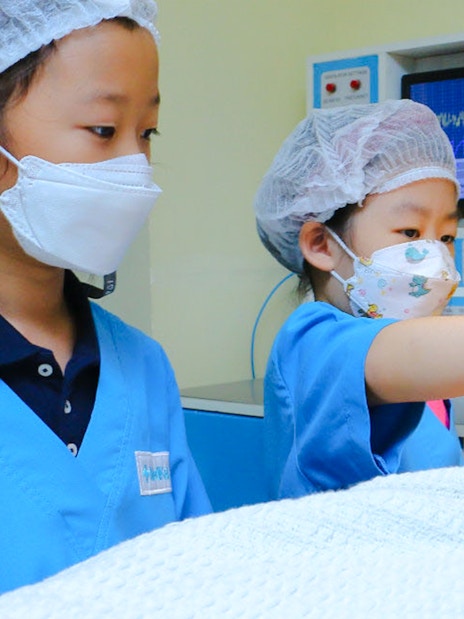 Children practicing surgery at KidZania with medical equipment.