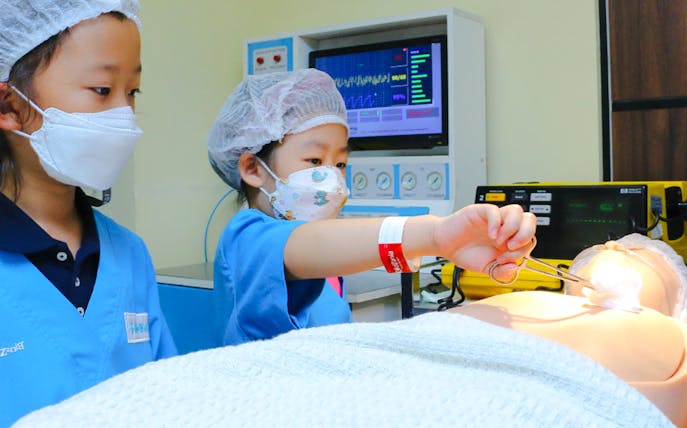Children practicing surgery at KidZania with medical equipment.