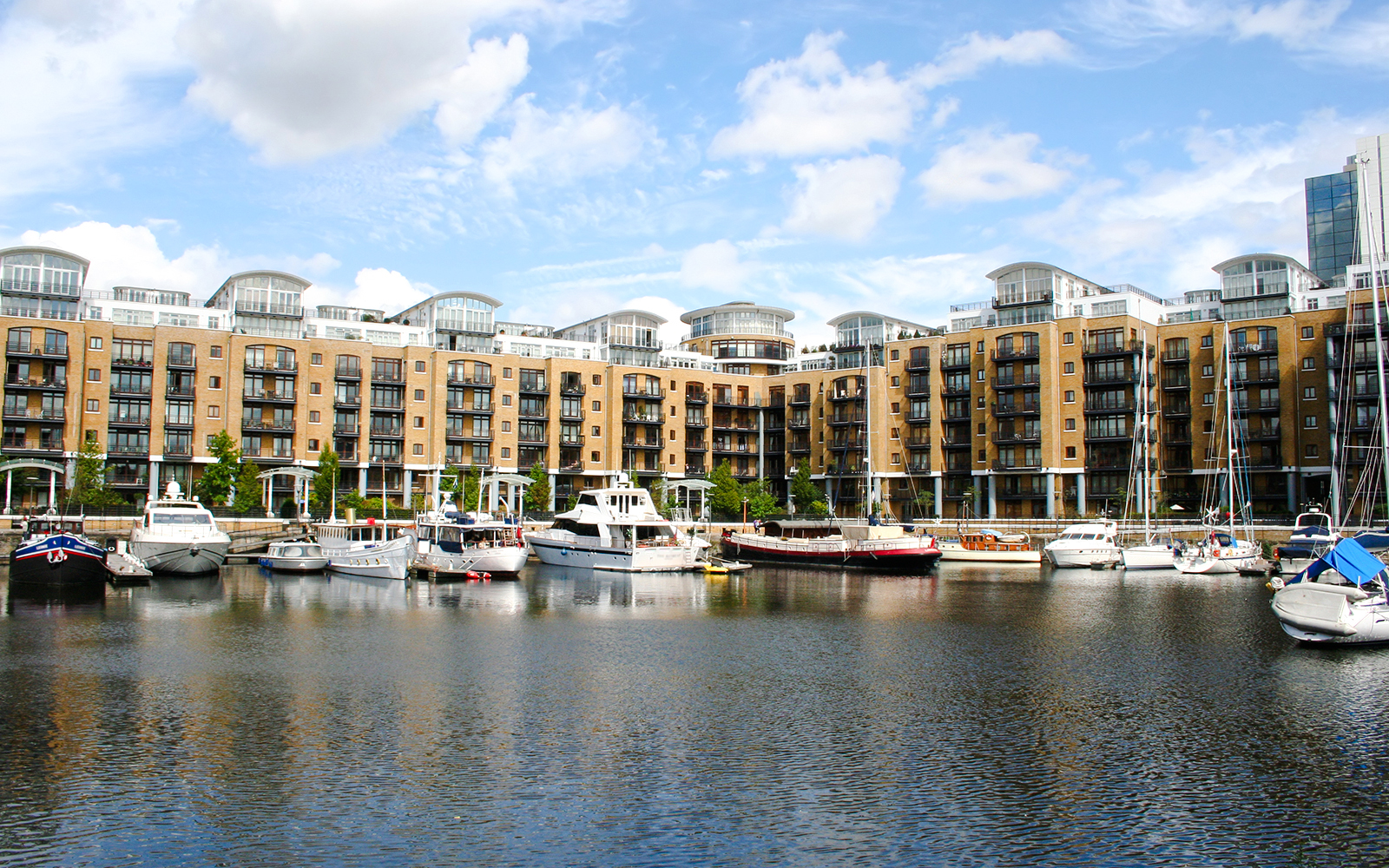 Boats docked at St Katharine's Dock, London, with modern apartments in the background.