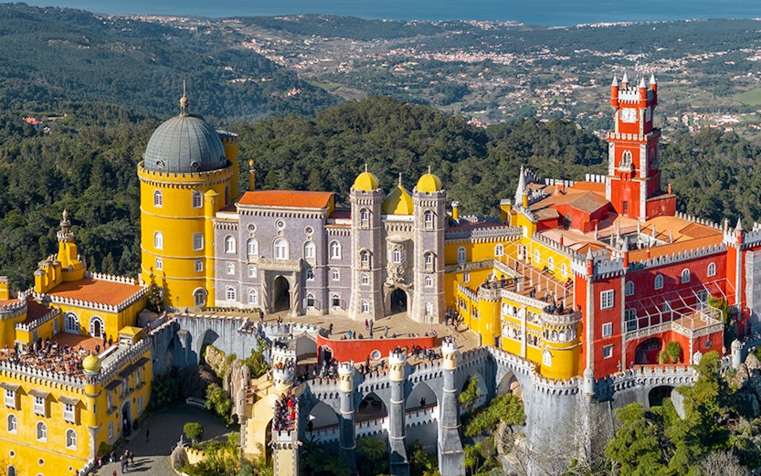 Pena Palace in Sintra, Portugal, with colorful towers and scenic forest backdrop.