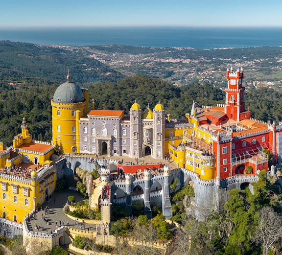 Pena Palace in Sintra, Portugal, with colorful towers and scenic forest backdrop.