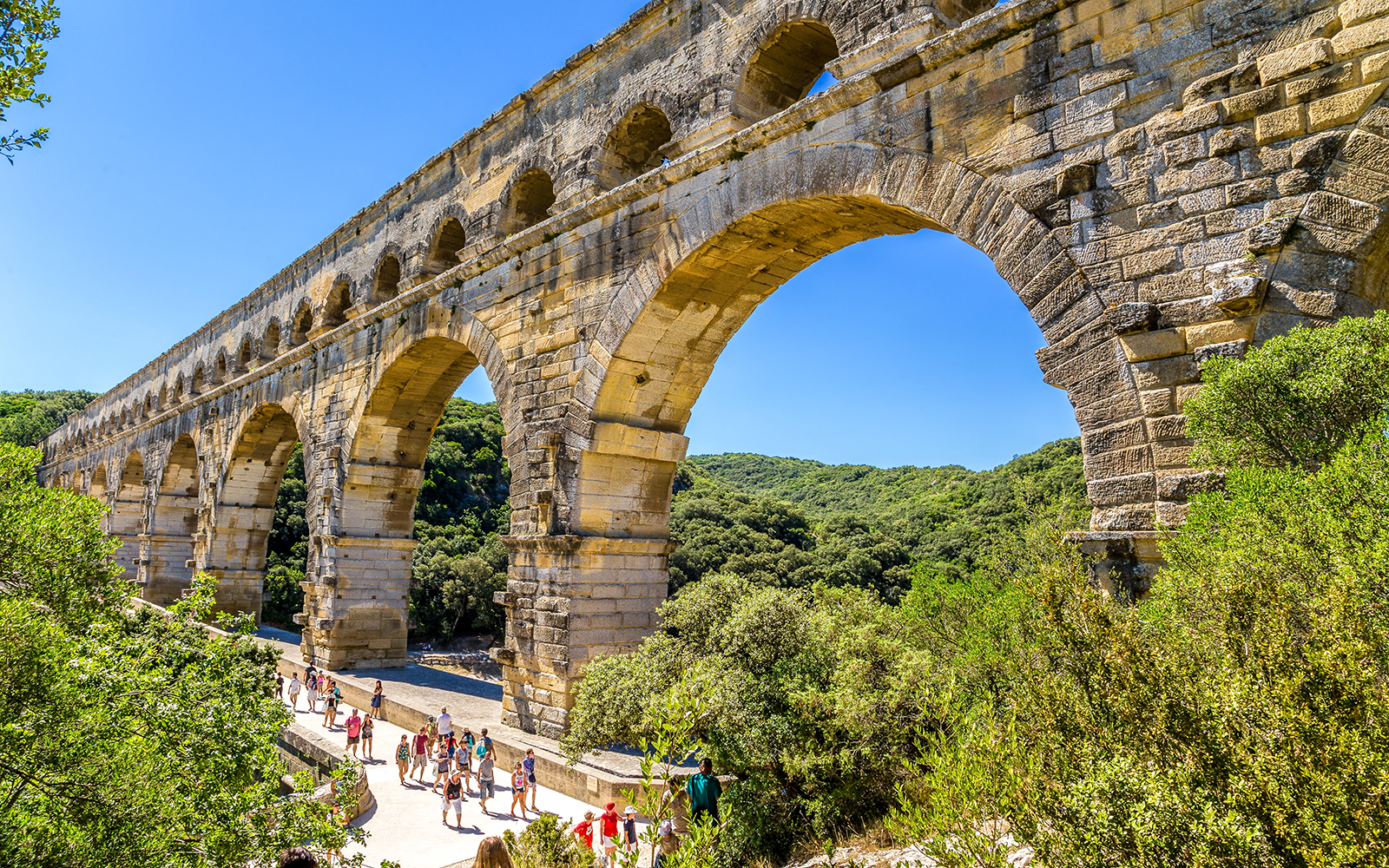 Visitors walking under the ancient Roman aqueduct Pont du Gard in France.