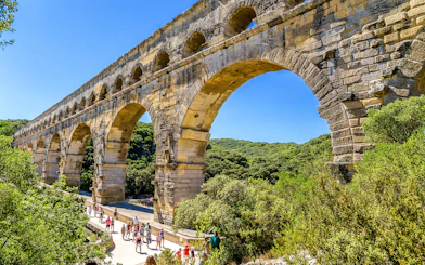 Visitors walking under the ancient Roman aqueduct Pont du Gard in France.