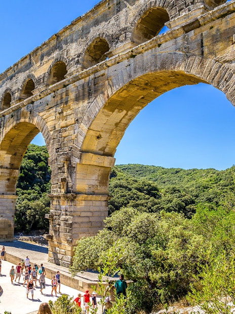 Visitors walking under the ancient Roman aqueduct Pont du Gard in France.
