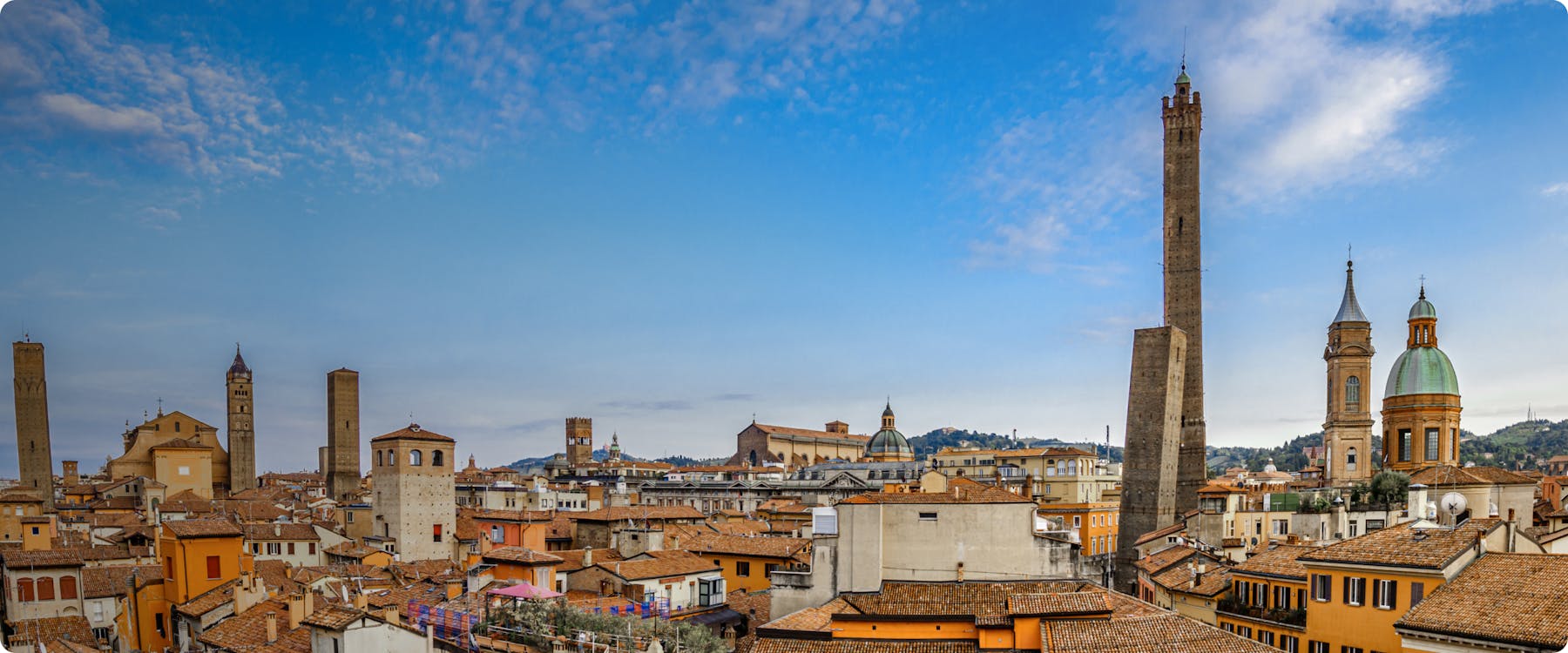 Bologna skyline with historic towers and red-tiled rooftops.