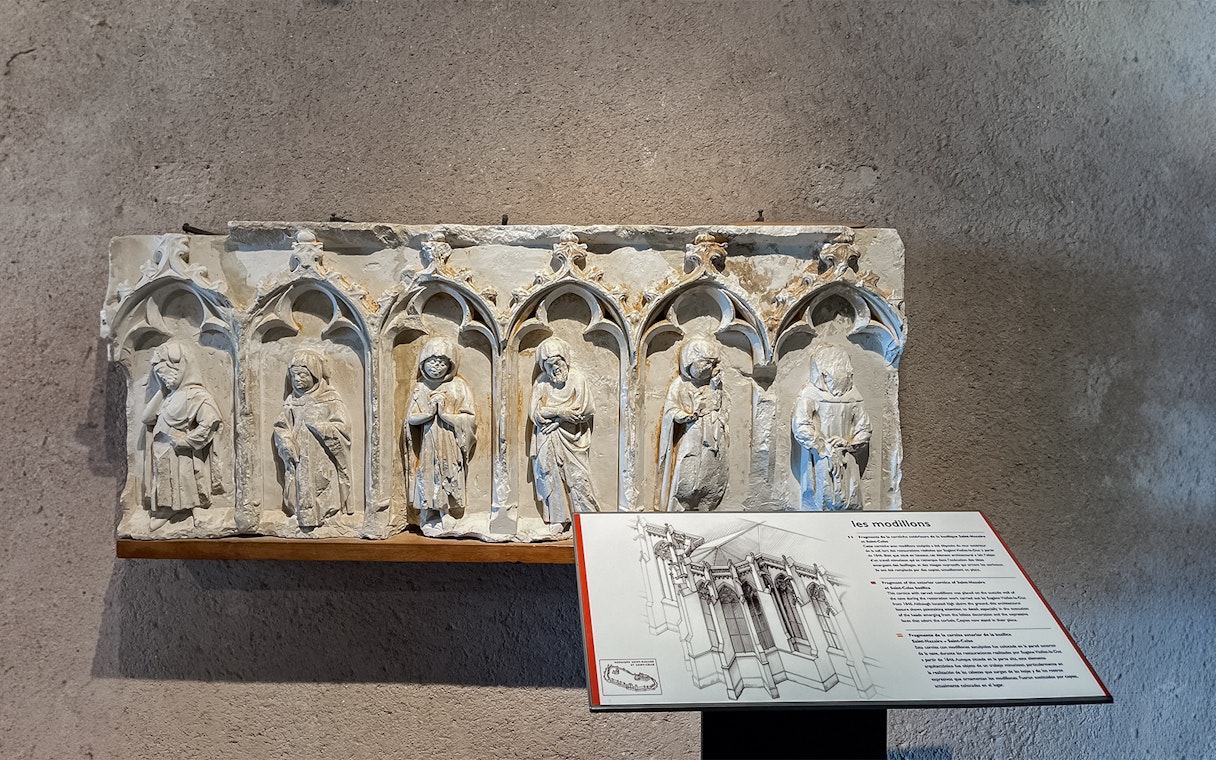 Carved stone figures in Carcassonne Castle museum exhibit with informational plaque.