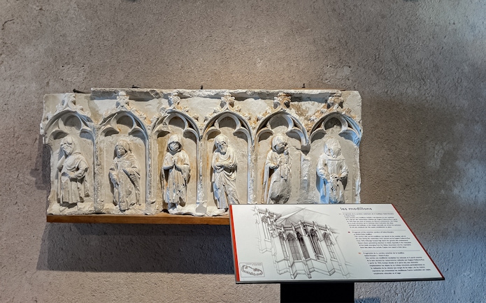 Carved stone figures in Carcassonne Castle museum exhibit with informational plaque.
