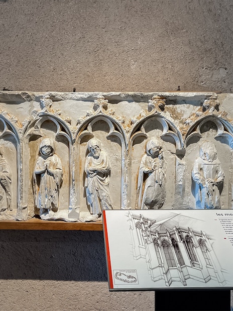 Carved stone figures in Carcassonne Castle museum exhibit with informational plaque.