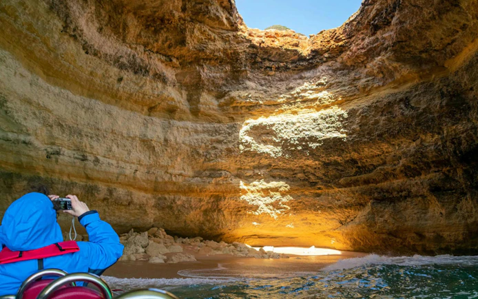Benagil Cave viewed from a boat, with a person taking photos, Portimao tour.