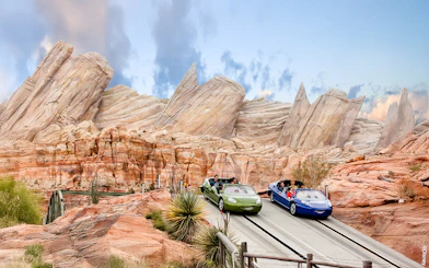 Cars on adventure track at Disneyland Adventure Park, California with rocky backdrop.
