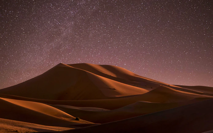 Starlit sky over sand dunes at Doha desert safari.