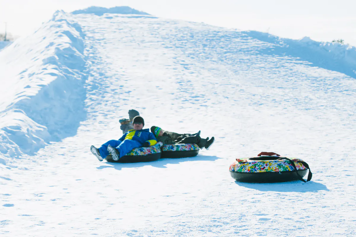 Children snow tubing on a slope during the Sapporo to Bibai Snow Land tour in Hokkaido.