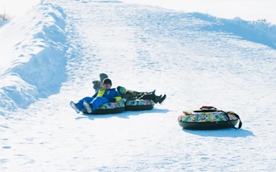Children snow tubing on a slope during the Sapporo to Bibai Snow Land tour in Hokkaido.