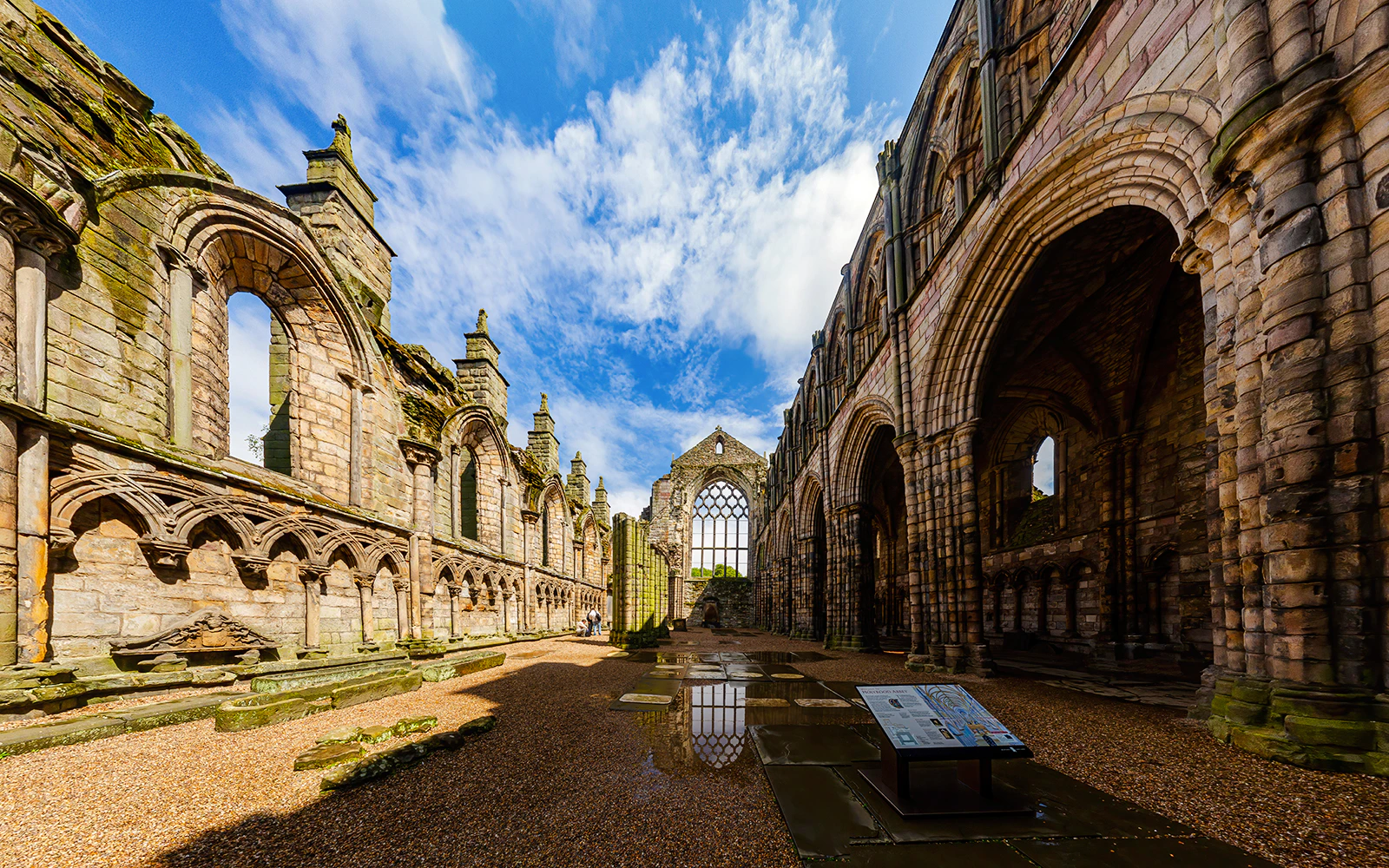 Ruins of Holyrood Abbey with stone arches and blue sky in Edinburgh, Scotland.