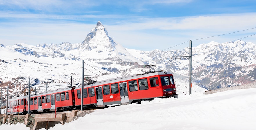 Gornergratbahn train approaching Gornergrat station with Matterhorn in the background.