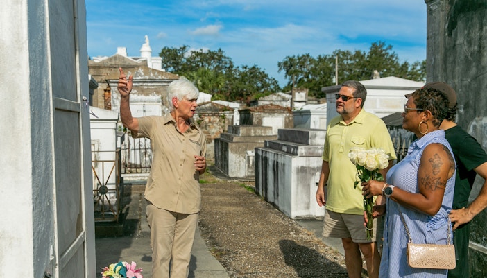 Tour guide explaining tombs to guests in St. Louis Cemetery, New Orleans.