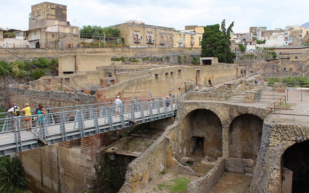 Visitors crossing a bridge towards the ancient ruins of Herculaneum, Italy.